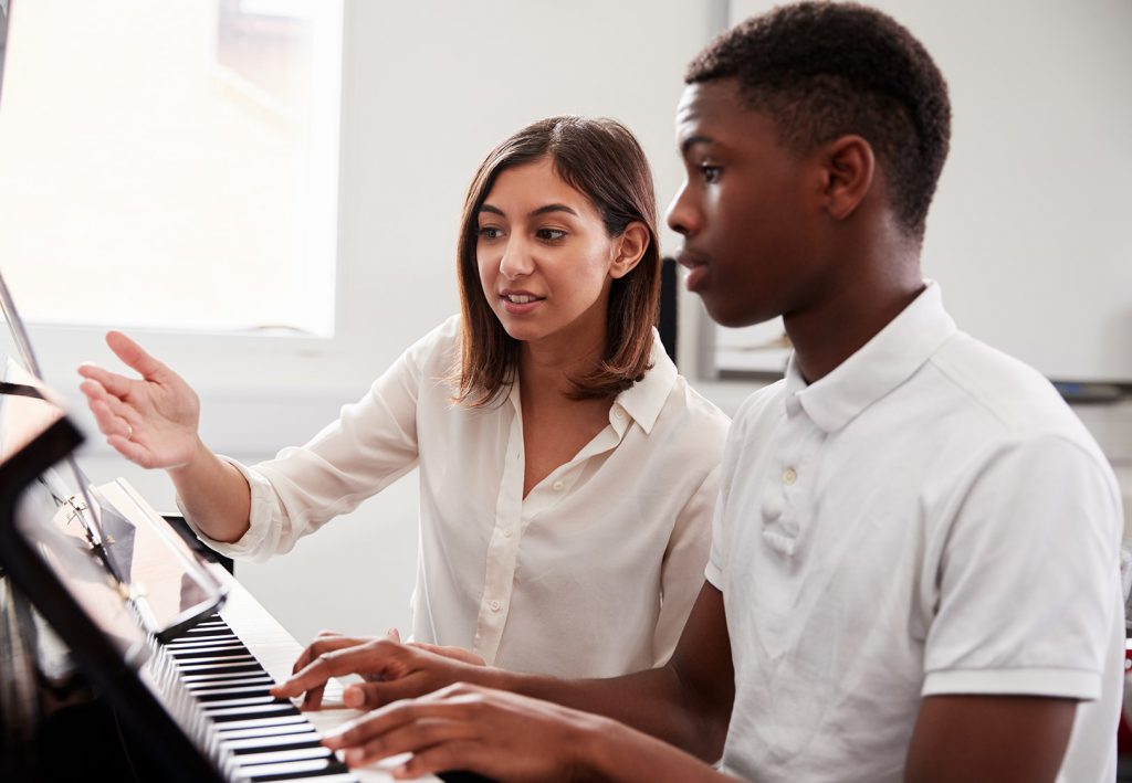 Professora ensinando aluno a tocar piano