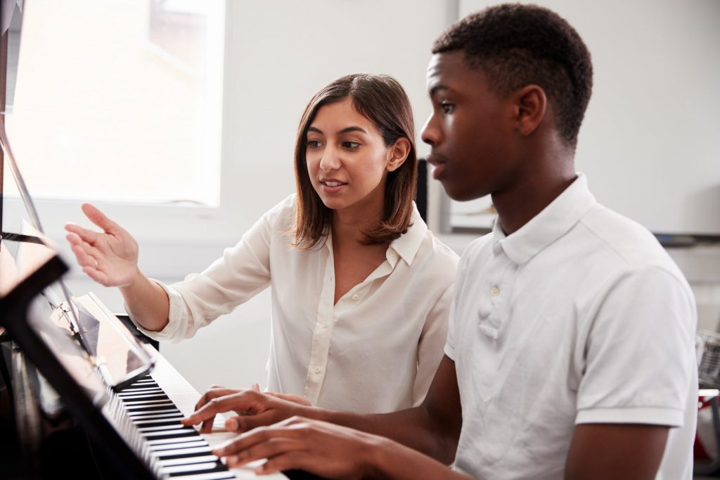 Professora ensinando piano para aluno