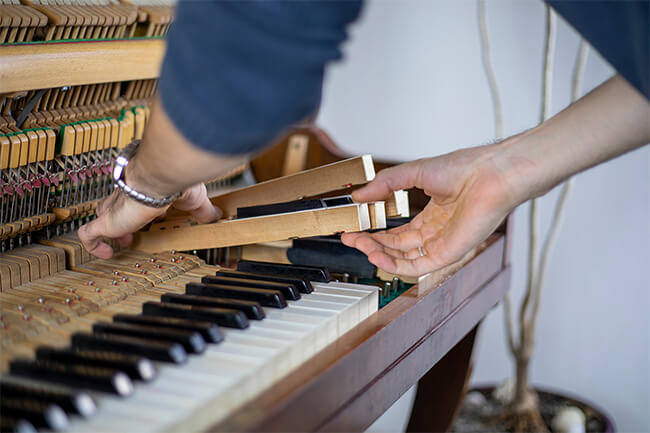 Pessoa realizando inspeção em componentes de um piano
